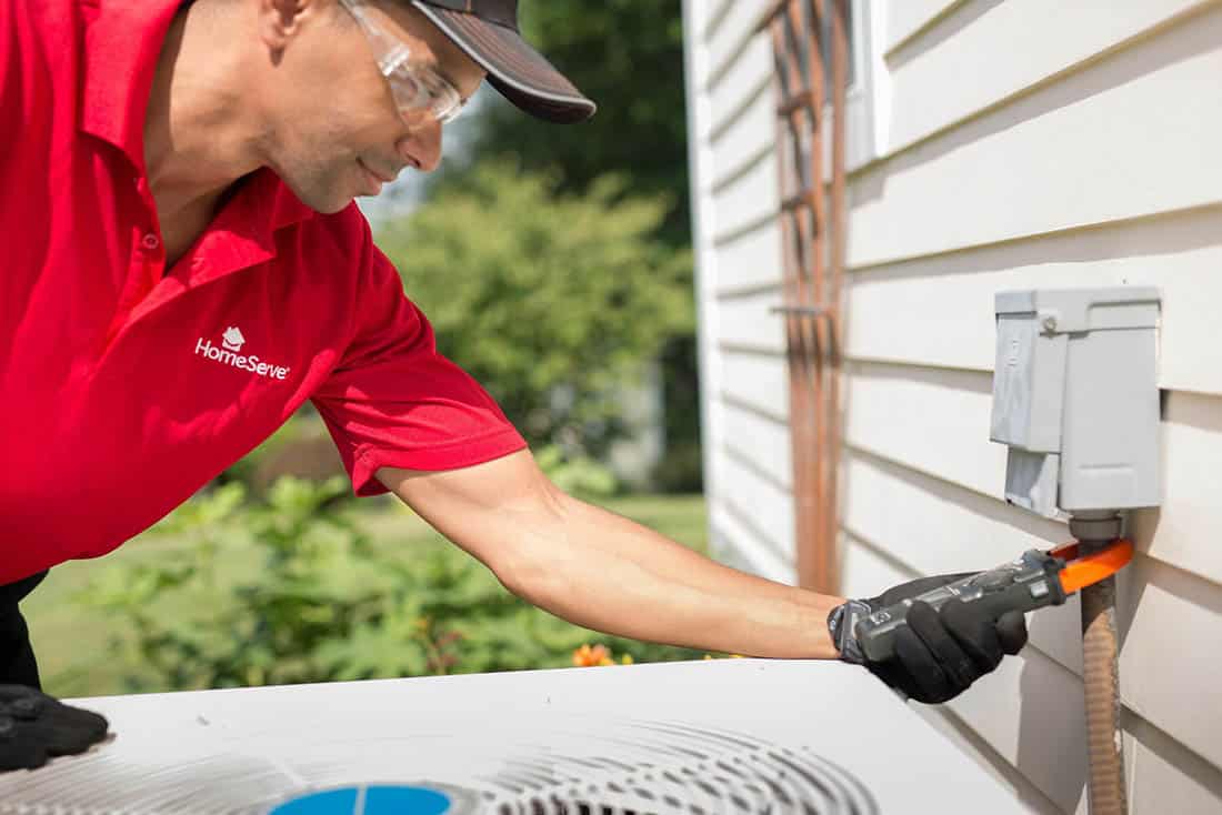 Service technician testing the HVAC meter on the side of the house after AC installation service