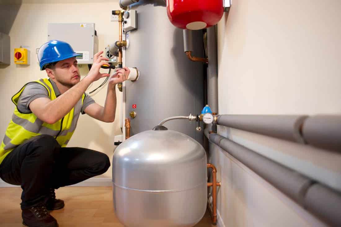 waterHeaters-WaterHeaterMaintenance-Supporting-1100×734 Service technician performing maintenance service on a tank water heater